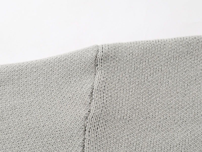 Close-up of light gray knit shoulder seam and ribbed collar transition