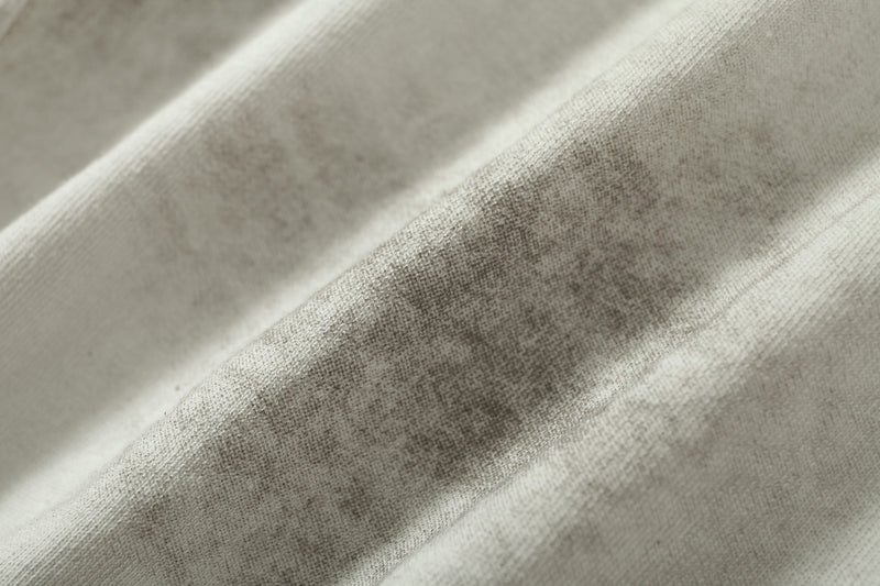 Close-up of distressed beige raglan tee fabric with worn texture and faded streetwear styling