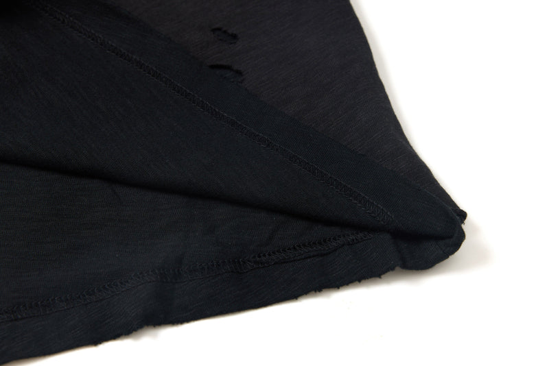 Close-up of a washed black distressed graphic tee with layered seams and raw hem detail