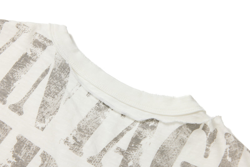 Close-up of an ivory distressed graphic tee collar with faded industrial print and layered fabric detail