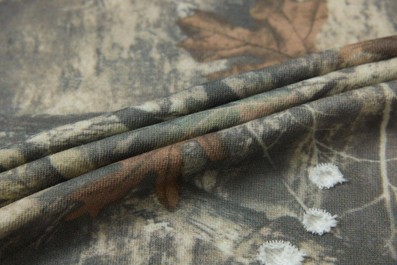 Close-up of a woodland camo crop tee with folded fabric, distressed details, and frayed white cutout accents