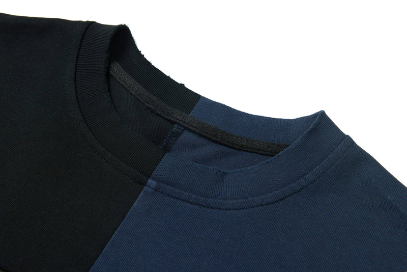 Close-up of a black and navy oversized graphic tee with distressed panel detailing and ribbed crew neckline