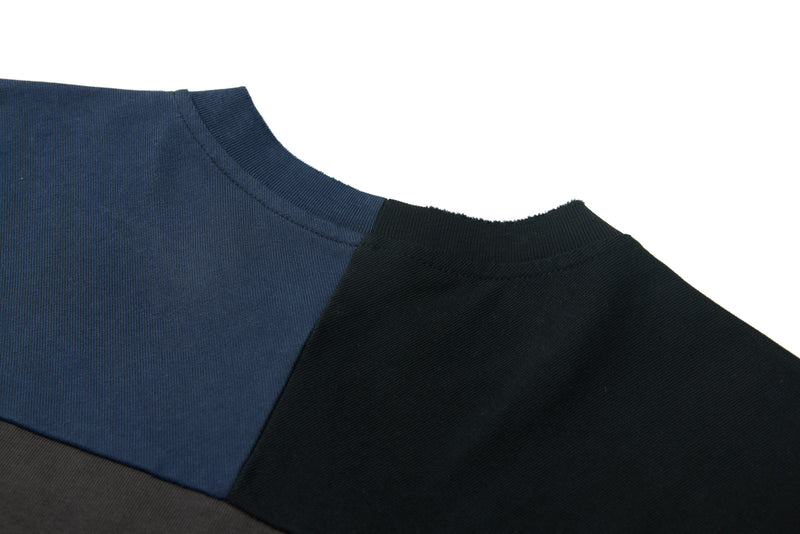 Close-up of an oversized panel graphic tee in navy, black, and charcoal with ribbed crew neck and distressed stitching details