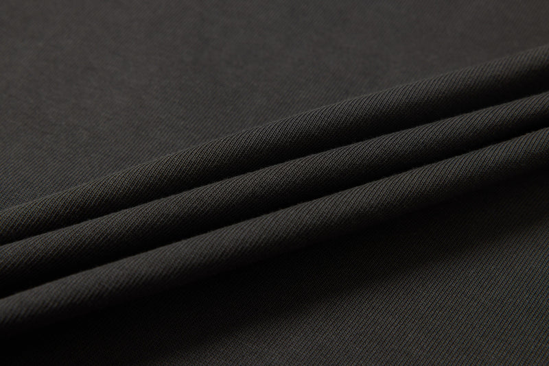 Black distressed panel graphic tee fabric with textured folded cotton, close-up streetwear detail