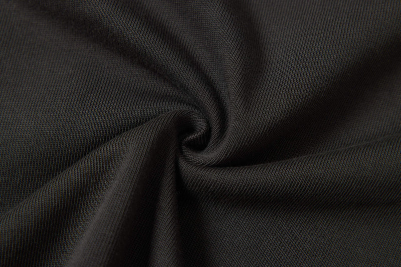 Close-up of black ribbed fabric with a twisted drape, showing the texture of an oversized streetwear tee