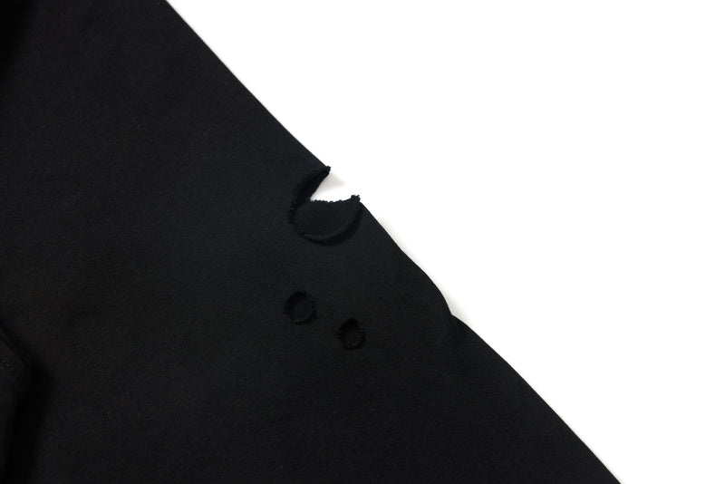Black tee side seam with distressed holes close-up