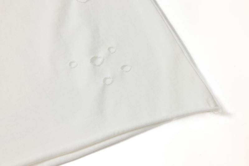 Close-up of white tee sleeve with clustered distressed hole details
