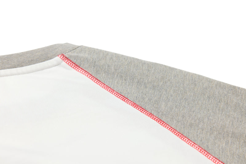 Close-up of the shoulder seam showing gray sleeve fabric and red overlock stitching
