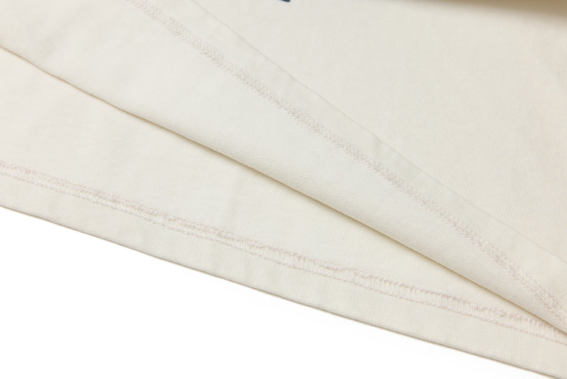 Close-up of white tee hem with neat overlock stitching and layered fabric edges