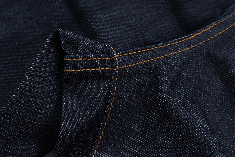 Close-up of denim waistband seam with brown topstitching and folded fabric detail