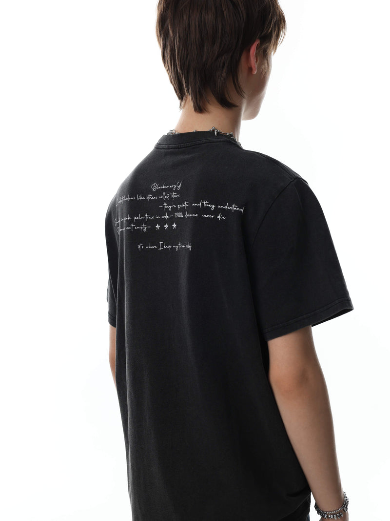 Black vintage washed graphic T-shirt with handwritten white text on the back, styled on a model against a white background
