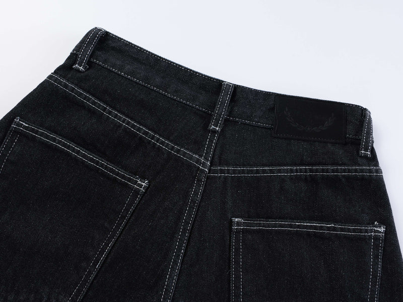 Back waistband and pockets of dark wash denim shorts with a black logo patch