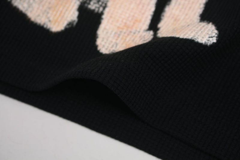 Close-up of black streetwear T-shirt fabric with a beige glitch-style cat graphic print