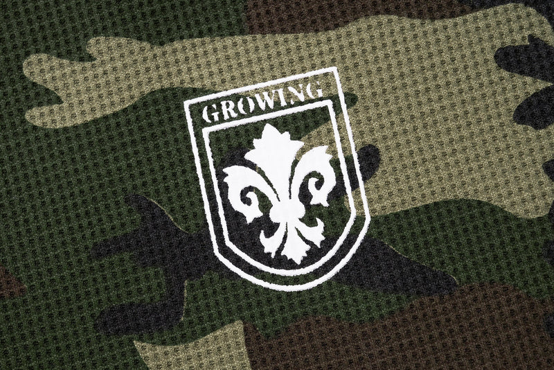 Close-up of white crest logo on green and brown camo fabric