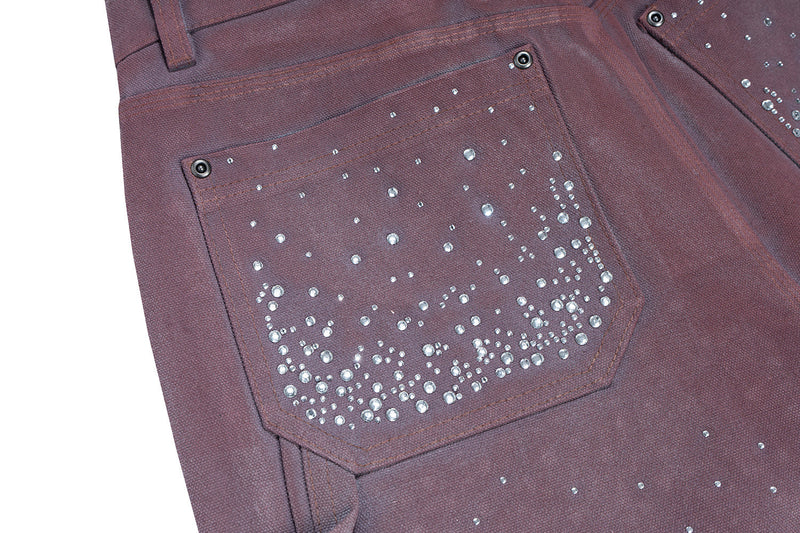 Close-up of back pocket with rhinestone embellishment on dark brown denim shorts