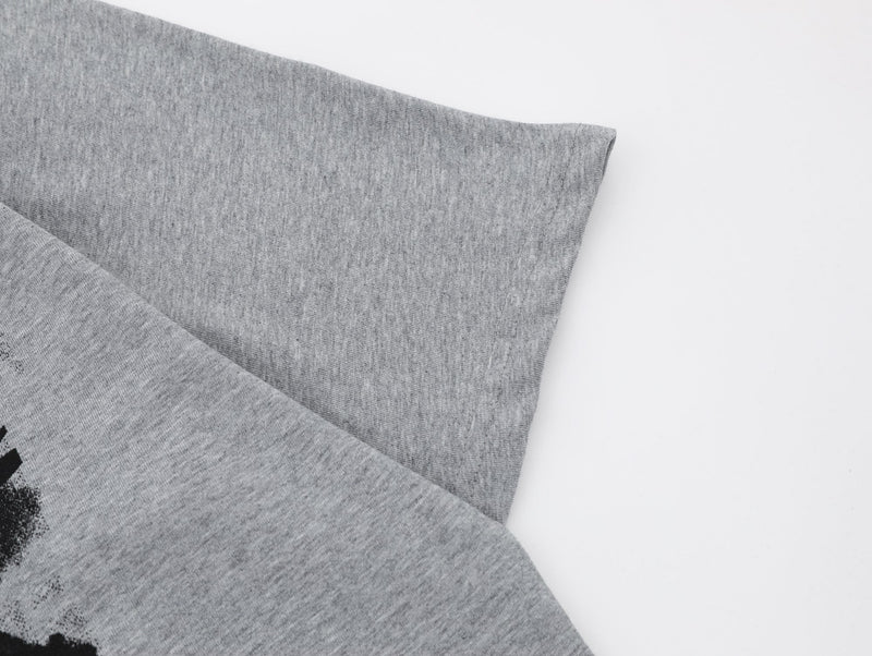 Close-up of a heather gray oversized graphic tee sleeve and hem with subtle black print on soft knit fabric