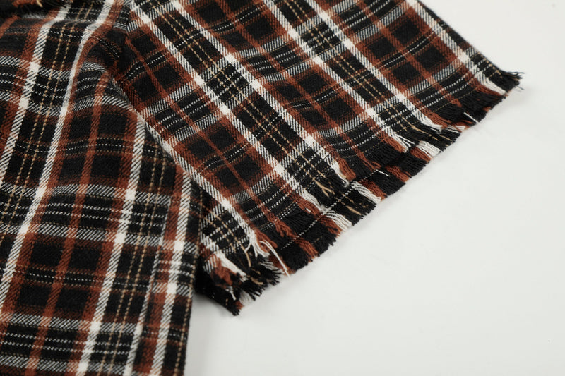 Distressed brown and black plaid shirt fabric with raw frayed hem on a clean white background