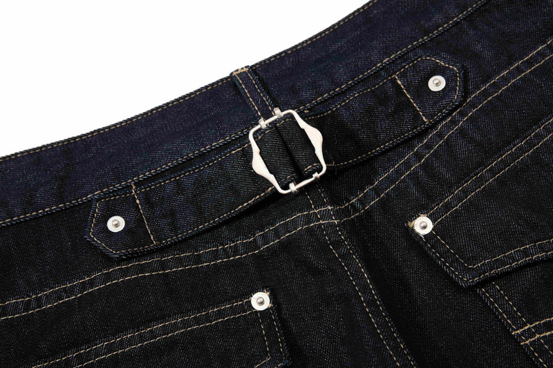 Close-up of the back waistband buckle on dark wash denim pants with stitched belt loops