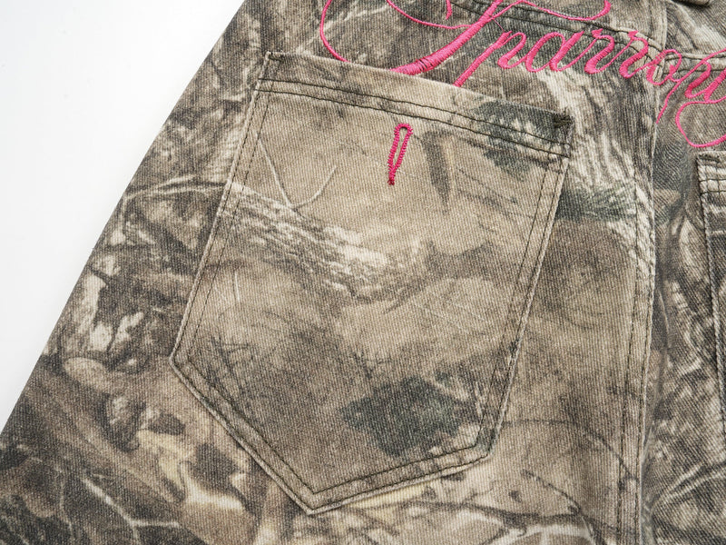 Close-up of back pocket on forest camo pants with pink embroidered detail
