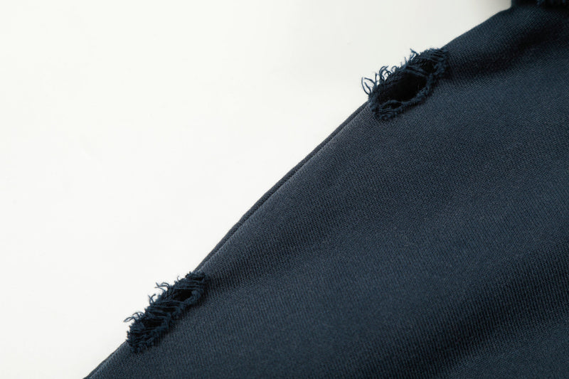 Close-up of frayed distressing along navy hoodie shoulder seam