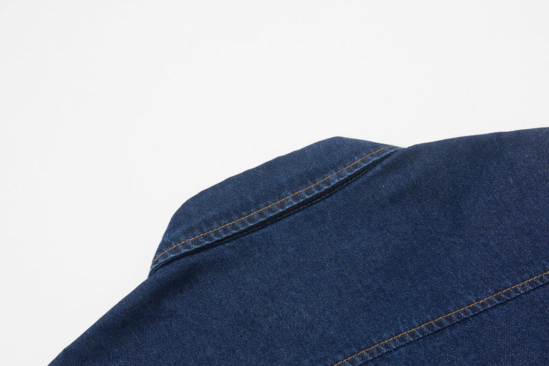 Close-up of a dark blue denim shirt shoulder with visible topstitching and seam detail
