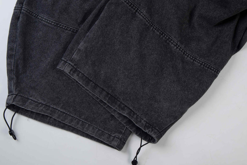 Close-up of black denim hem with drawstring cord and stitched cuff detail