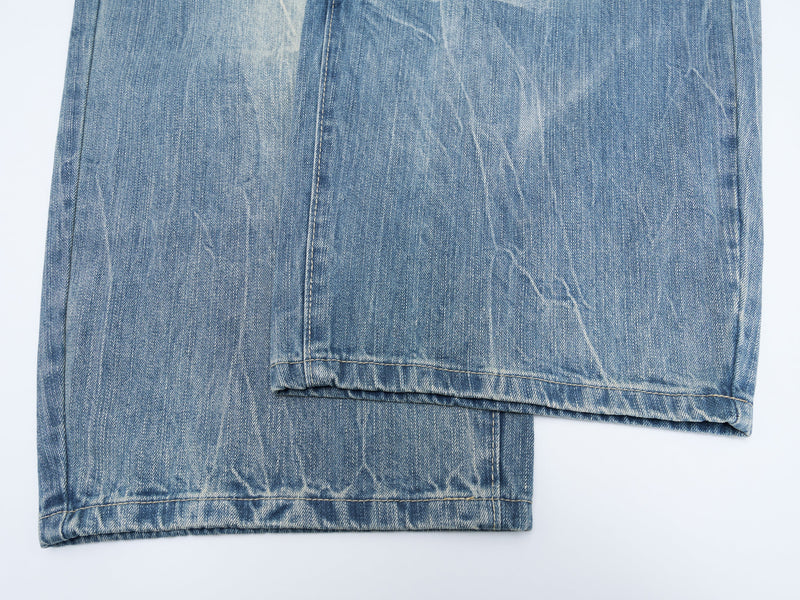 Cropped view of denim pant hems showing straight wide-leg cuffs and worn wash texture