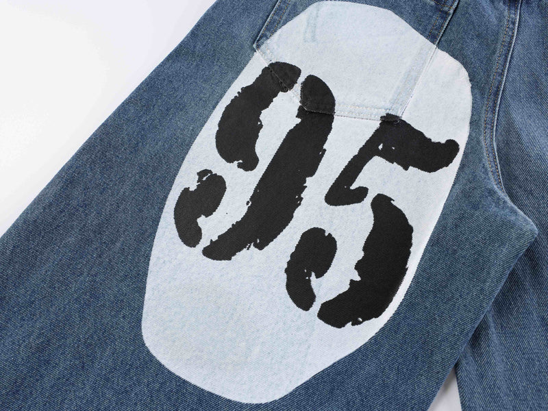 Close-up of blue denim leg with large white graphic panel and black lettering