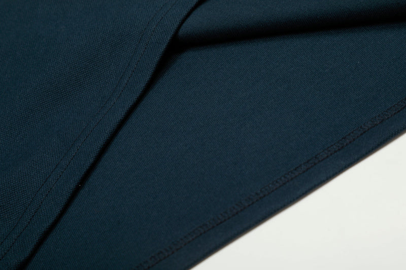 Close-up of navy tee side seam and sleeve stitching on textured fabric