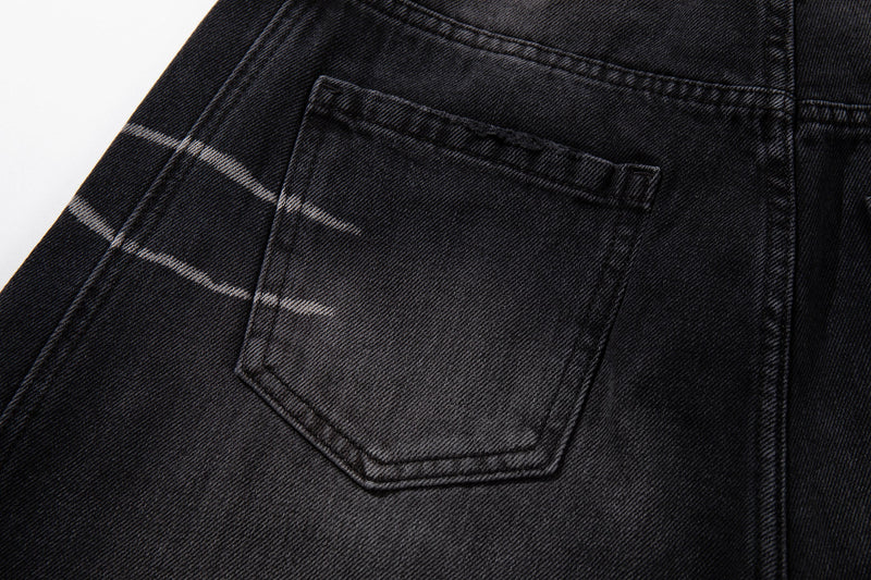 Close-up of back pocket on washed black denim with scratch-fade lines and contrast stitching