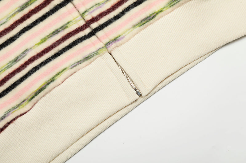 Close-up of cream ribbed hem and zipper on striped knit zip hoodie