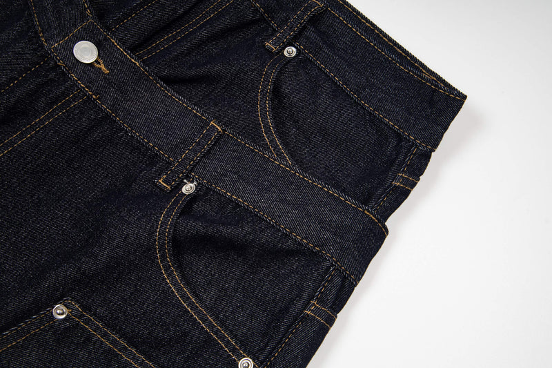 Close-up side view of dark wash denim shorts with layered waistband and rivets