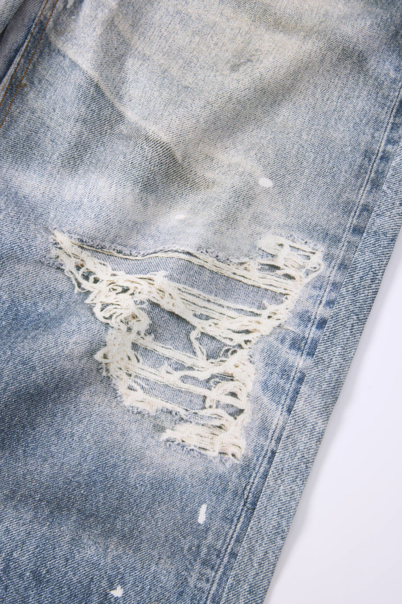 Close-up of heavy distressed rip on light wash denim leg