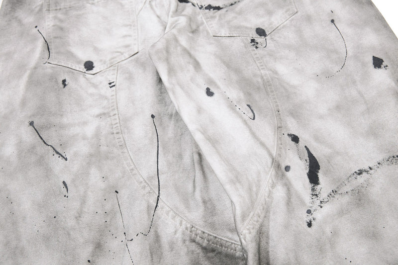 Close-up of front thigh area on gray jeans with black splatter and seam lines