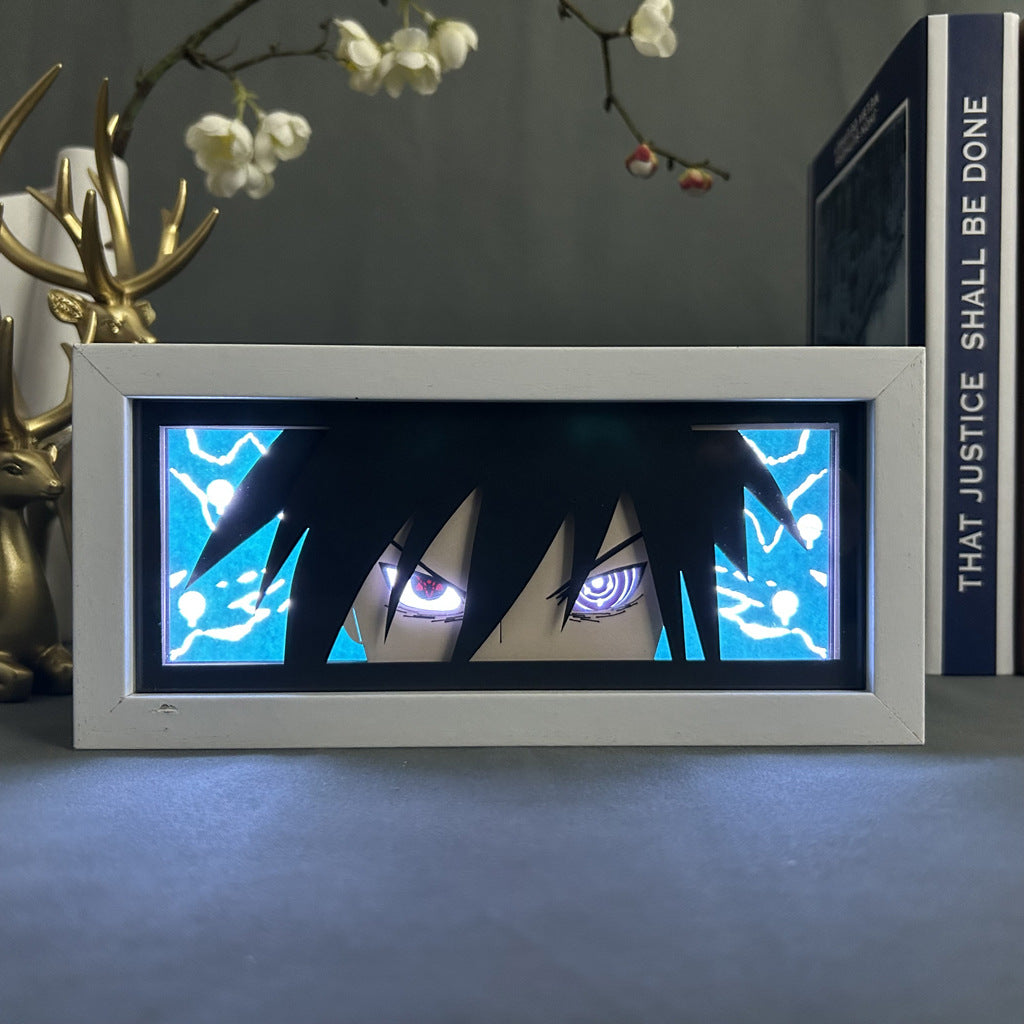 The Sasuke Uchiha LED Light Box from Naruto features a rectangular frame showcasing an anime-style eye with Sharingan & Rinnegan, intense expression, and striking lightning. With decorative elements like a deer figure and the book "That Justice Shall Be Done," it&