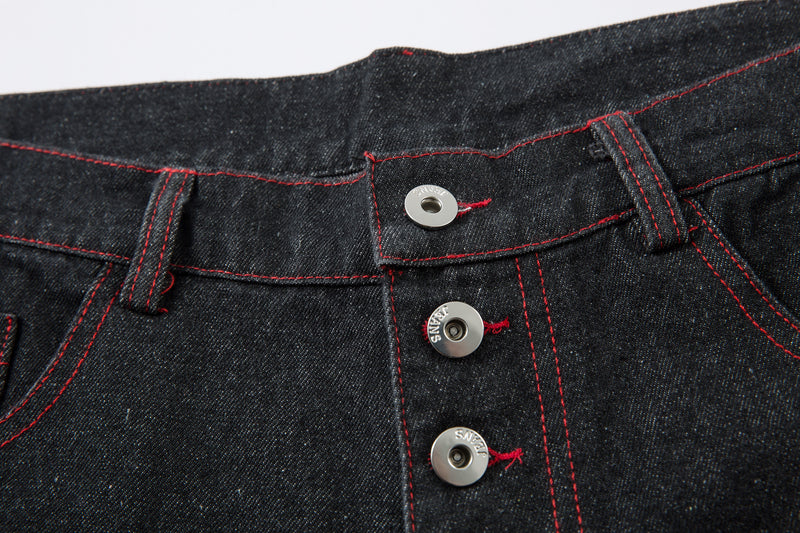 Close-up of the front waistband and three top buttons with red stitched seams