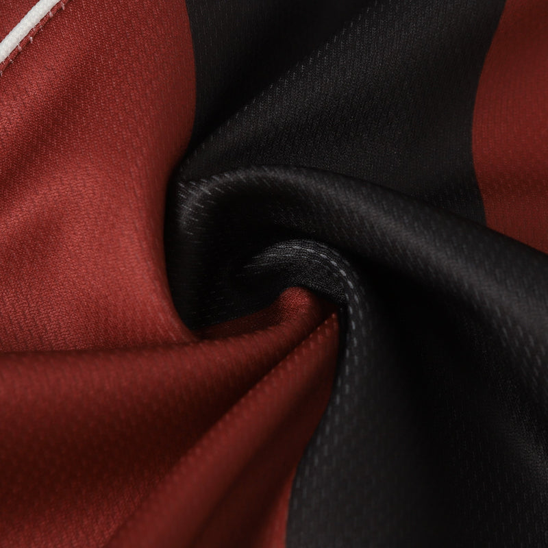 Close-up of red and black vertical striped soccer jersey fabric with white piping and stitched detailing