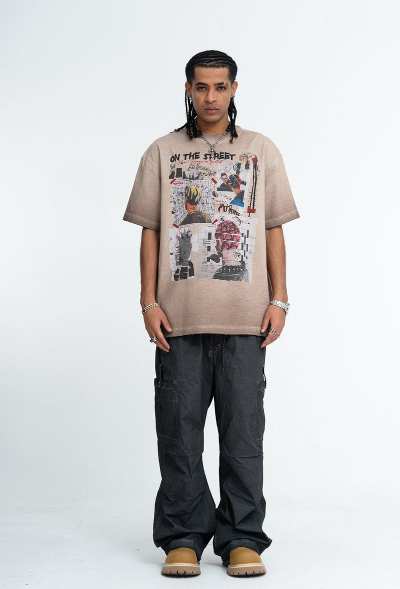 Model wearing a vintage wash beige graphic tee with collage print, paired with loose black cargo pants and tan boots