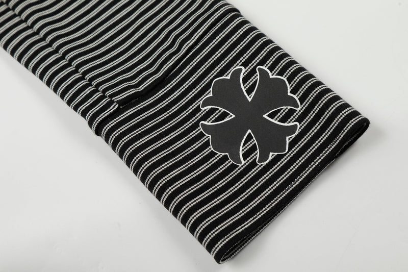 Close-up of sleeve cuff with white cross-style graphic on black striped hoodie