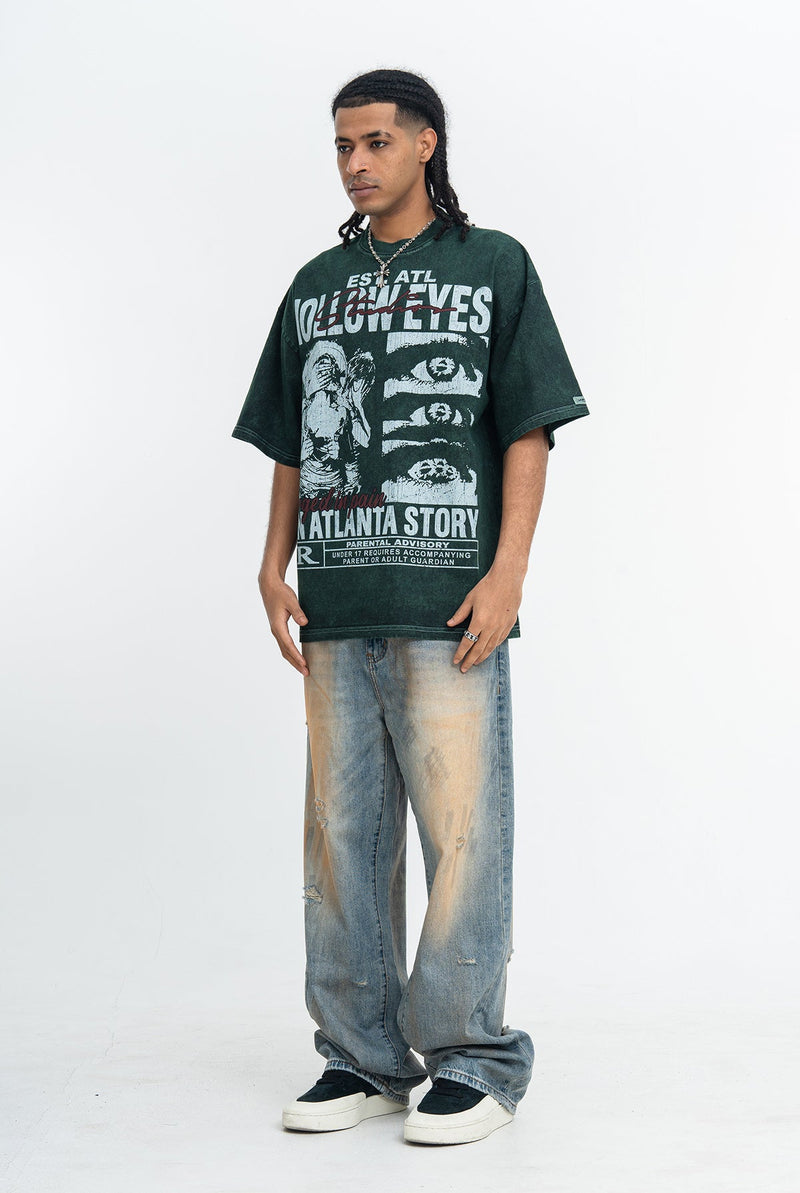 Model wearing a dark green vintage washed Atlanta story graphic tee with oversized distressed jeans and platform sneakers