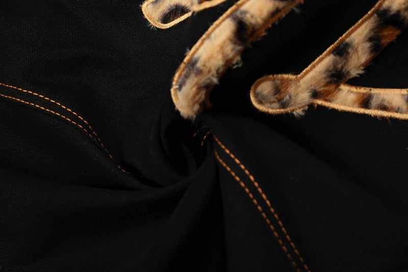 Close-up of leopard patch lettering detail on black wide-leg pants