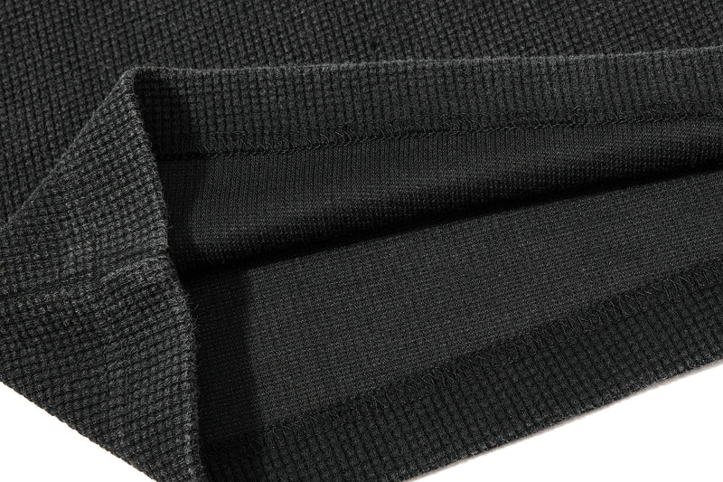 Close-up of a black waffle knit graphic T-shirt with folded fabric texture and ribbed hem detail