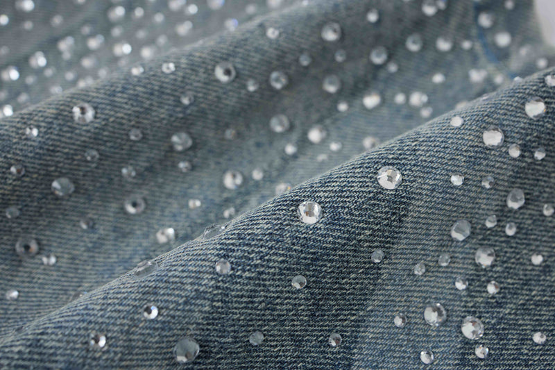 Close-up of rhinestones on light wash denim fabric