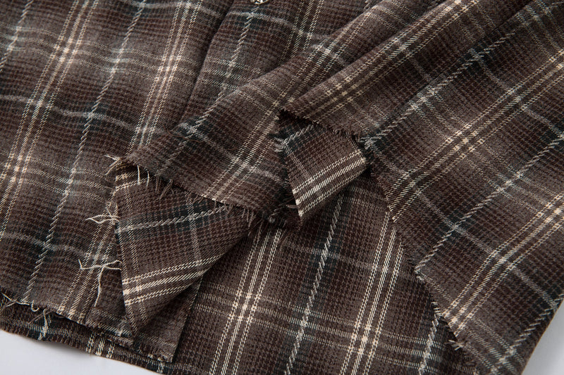 Close-up of distressed brown plaid sleeve and frayed hem
