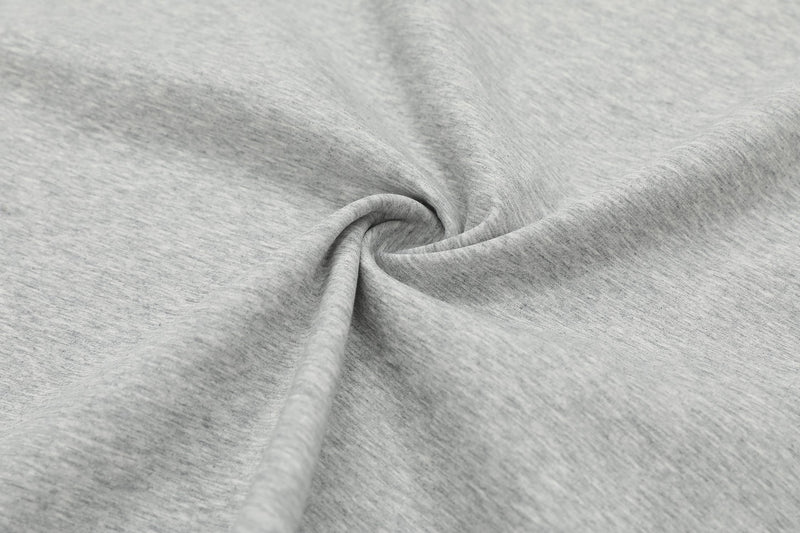 Close-up of light gray heathered fabric with a soft twisted drape, showing the structured oversized tee material texture