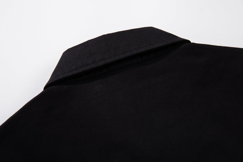 Close-up of a black button-up shirt collar and shoulder with smooth fabric and subtle streetwear styling