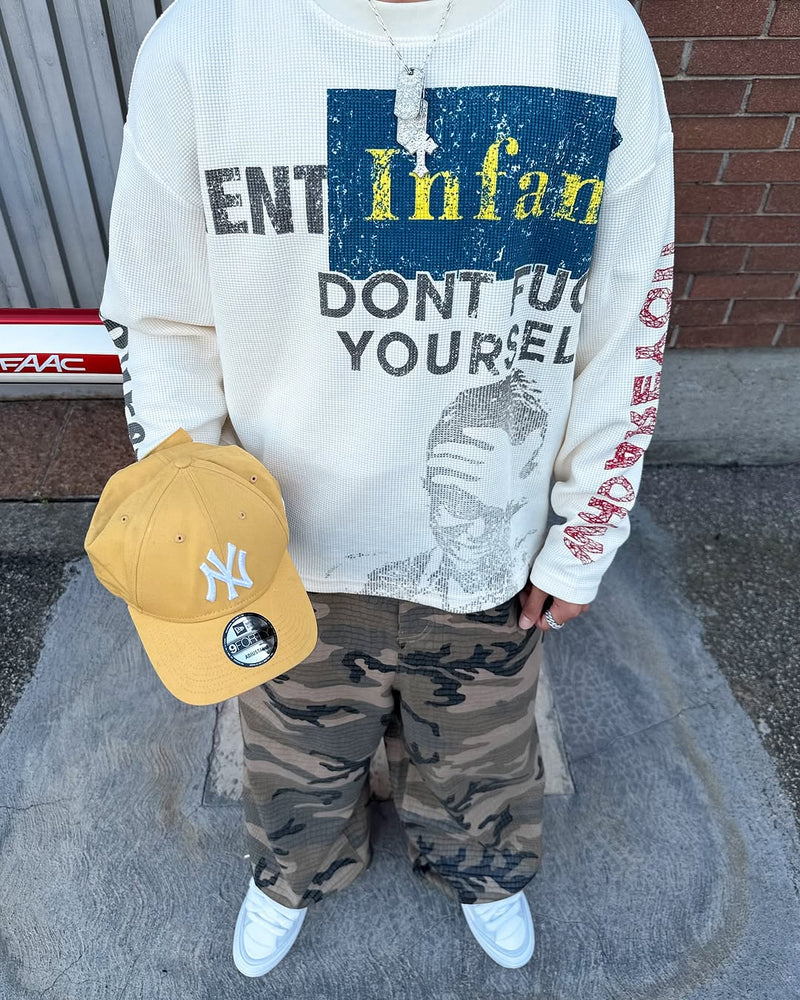 Front view of cream graphic long sleeve shirt worn with camo pants and yellow cap