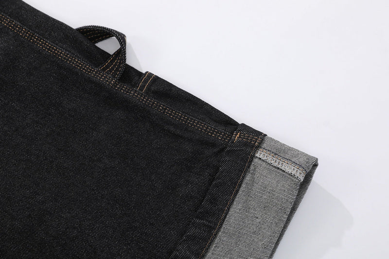 Close-up of black denim shorts hem with gray raw-edge cuff stitching