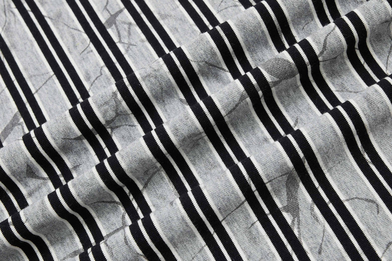 Close-up of a black and gray striped cotton T-shirt with crinkled texture and graffiti-style pattern details