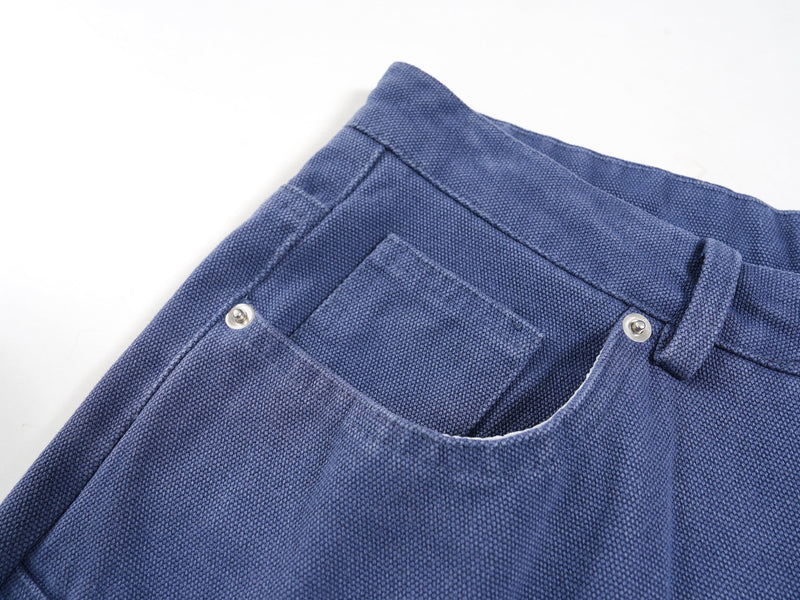 Close-up of blue jorts waistband and front pocket with metal rivets and textured canvas weave